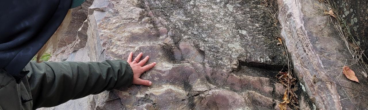 person touching feature in rock